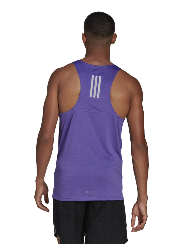 Hombre vistiendo camiseta deportiva sin mangas color morado de la marca Adidas con logo reflectante en el pecho.