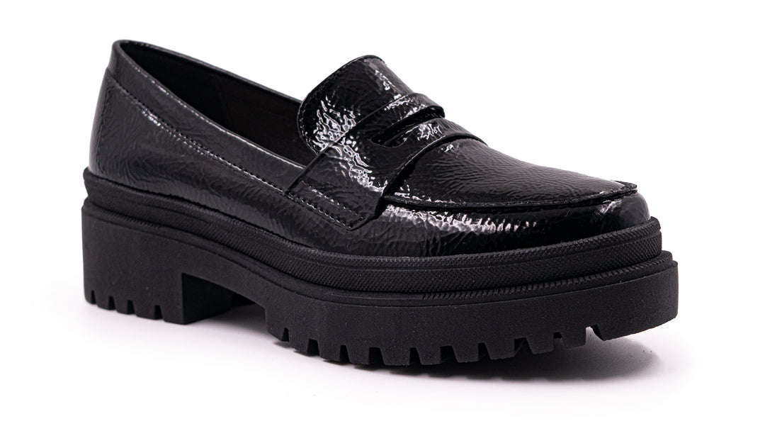 Zapato tipo mocasín negro de alto brillo con suela de plataforma gruesa y dentada.