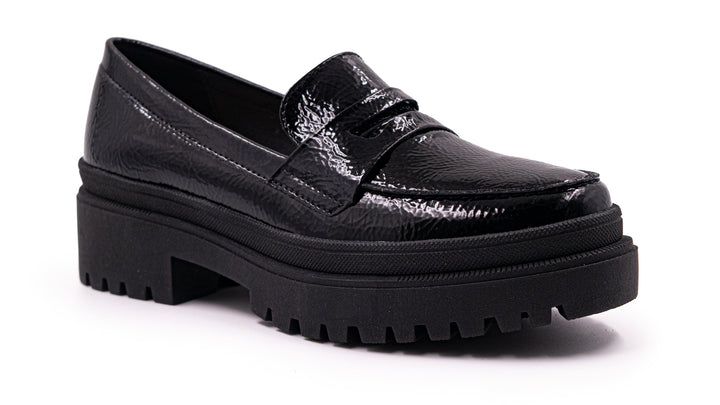 Zapato tipo mocasín negro de alto brillo con suela de plataforma gruesa y dentada.