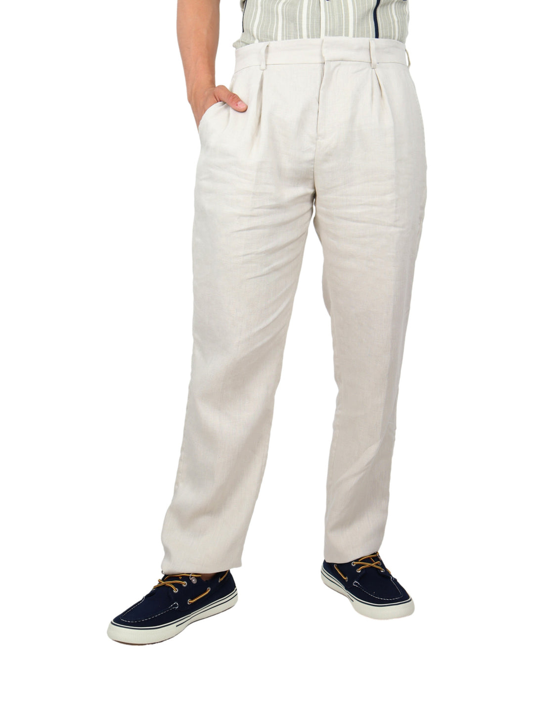 Hombre vistiendo pantalón color beige con pinzas y calzado azul marino sobre fondo blanco.