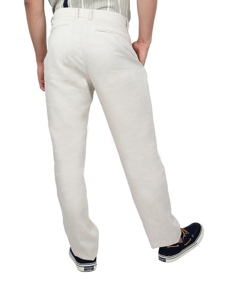 Hombre vistiendo pantalón color beige con pinzas y calzado azul marino sobre fondo blanco.