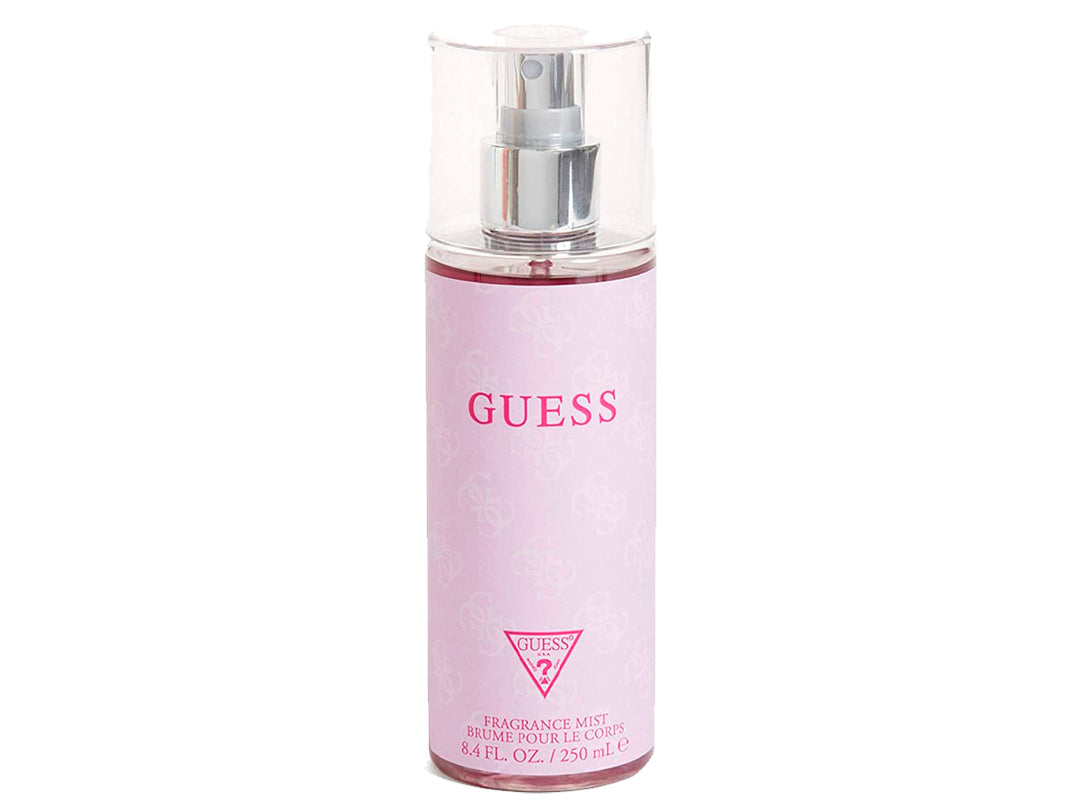 Botella cilíndrica de bruma corporal GUESS en color rosa pastel con tapa transparente y atomizador plateado.