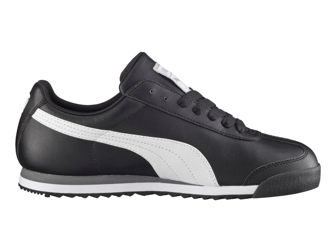 Tenis Puma Roma Basic color negro con franja blanca lateral y suela blanca y gris.