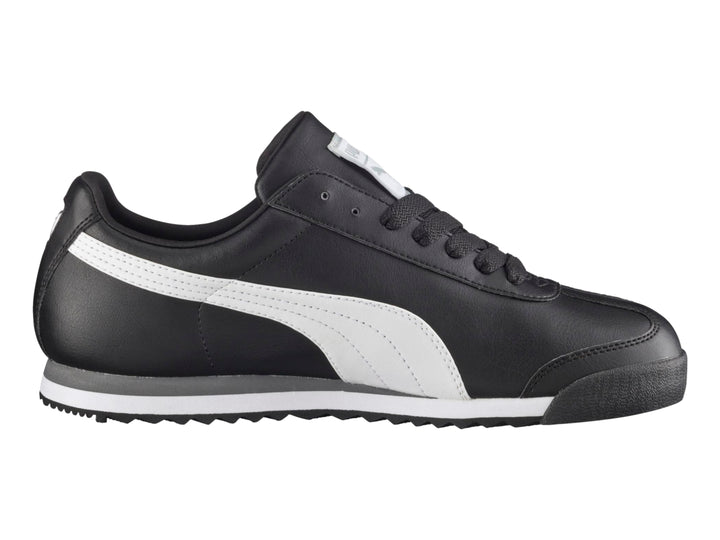 Tenis Puma Roma Basic color negro con franja blanca lateral y suela blanca y gris.
