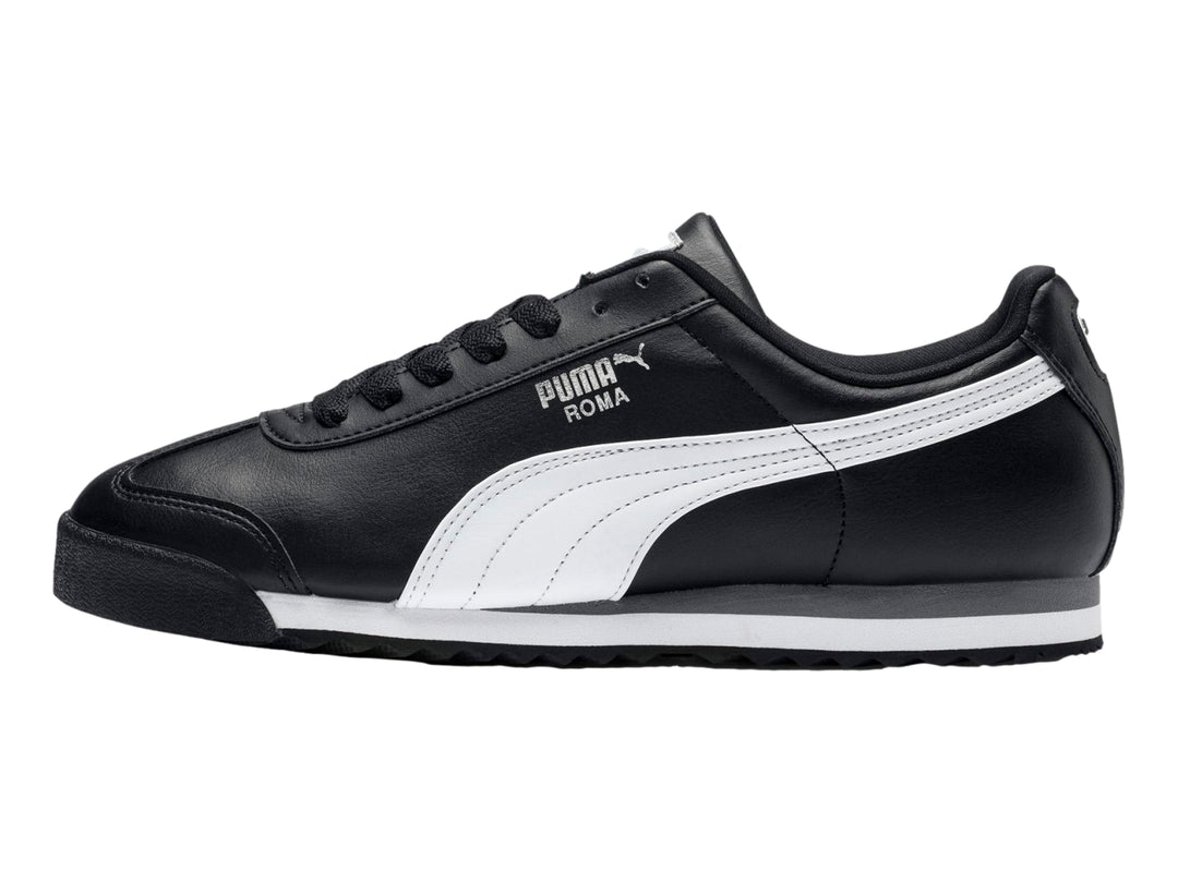 Tenis Puma Roma Basic color negro con franja blanca lateral y suela blanca y gris.
