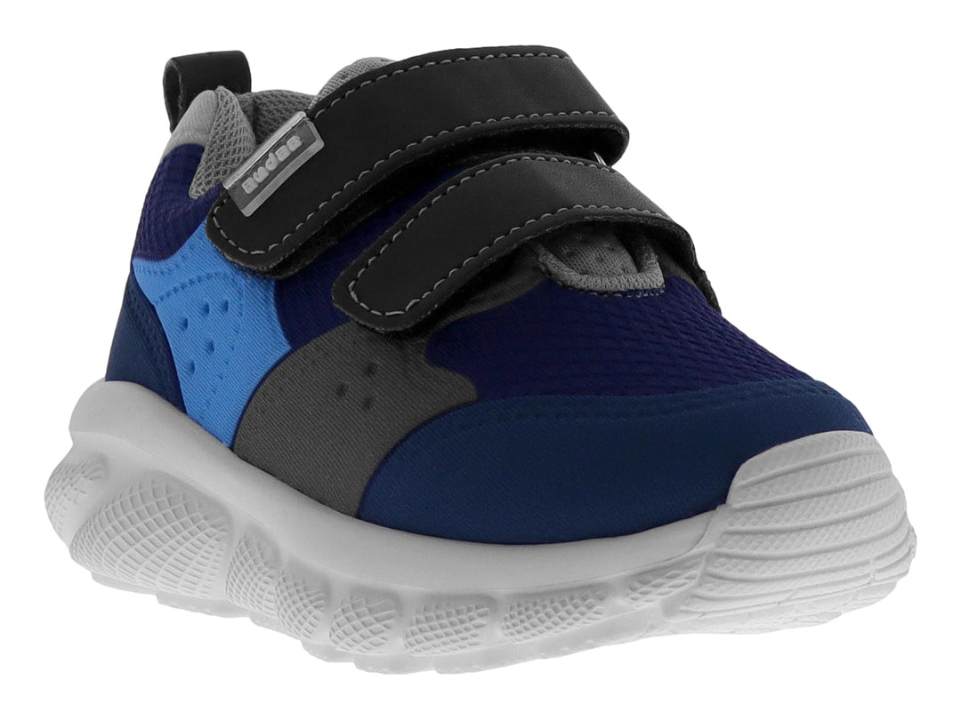 Tenis deportivo infantil en tonos azul y gris con cierre de velcro y suela blanca.