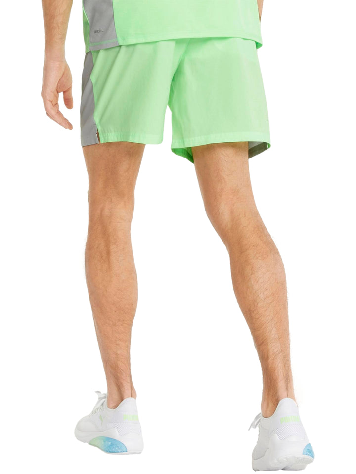 Hombre vistiendo shorts deportivos PUMA color verde lima con logo blanco en la pierna izquierda.