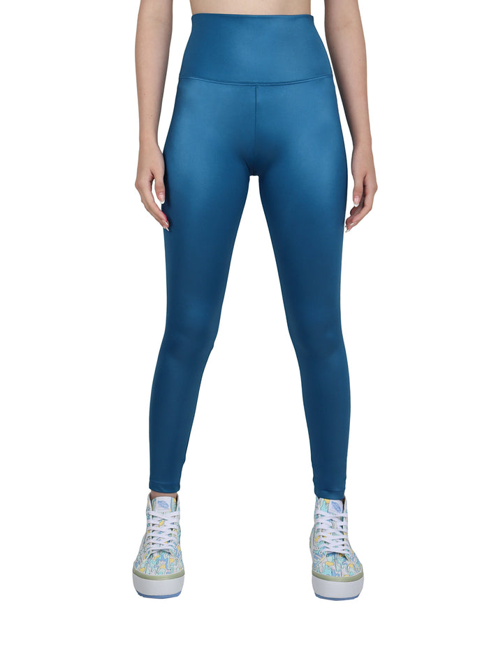 Mujer vistiendo leggings deportivos de color petroleo con talle alto y acabado brillante.