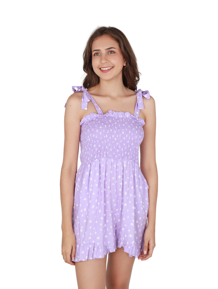 Mujer vistiendo un romper corto color lila con lunares blancos y tirantes ajustables.
