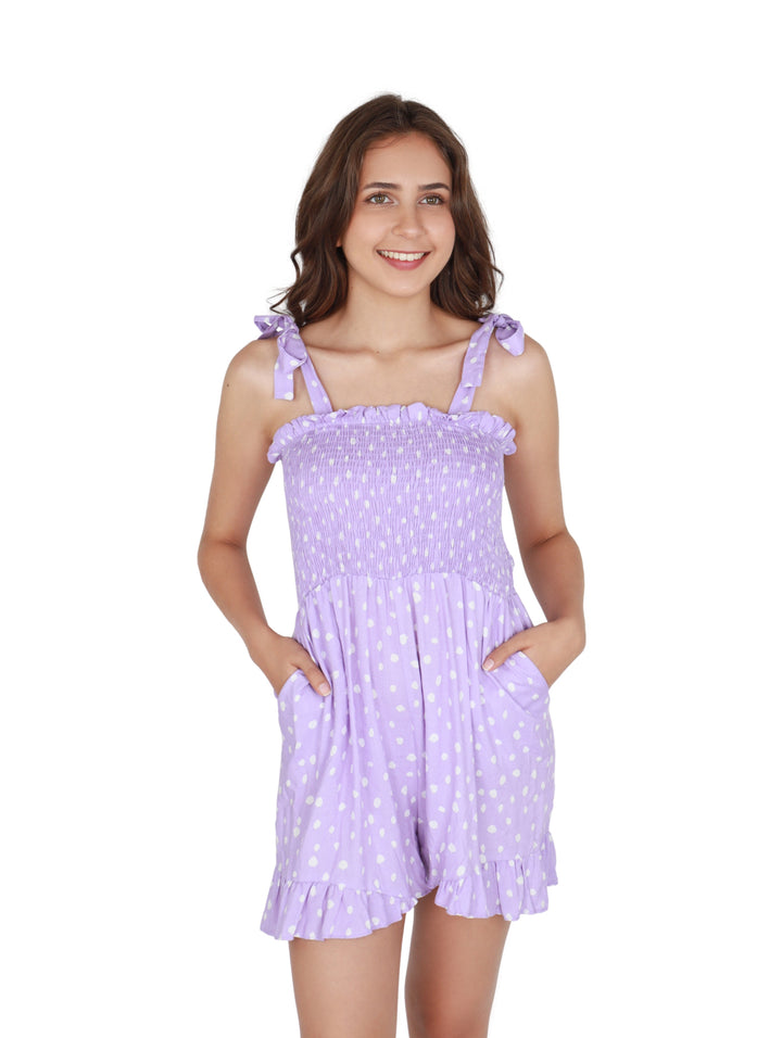 Mujer vistiendo un romper corto color lila con lunares blancos y tirantes ajustables.