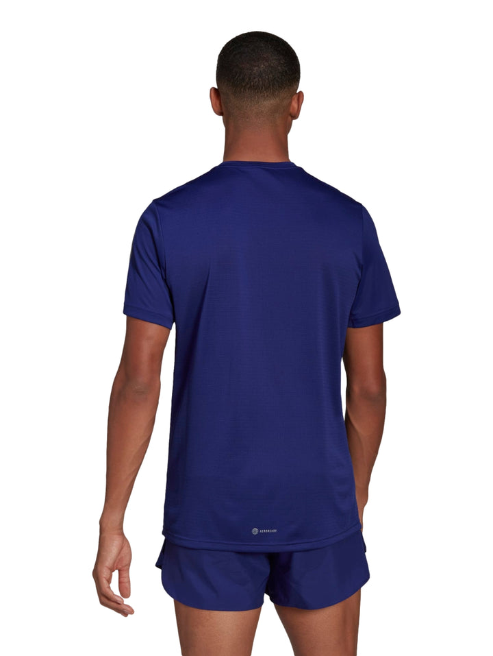 Hombre vistiendo camiseta deportiva Adidas color azul índigo con detalles plateados en los hombros.