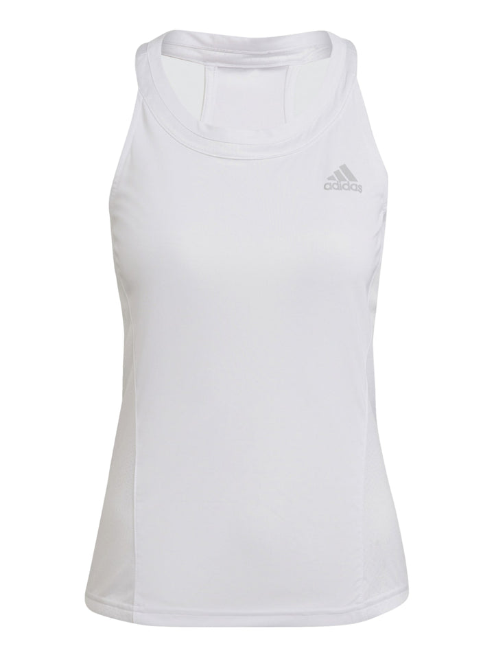Mujer con camiseta deportiva blanca sin mangas Adidas y falda negra.