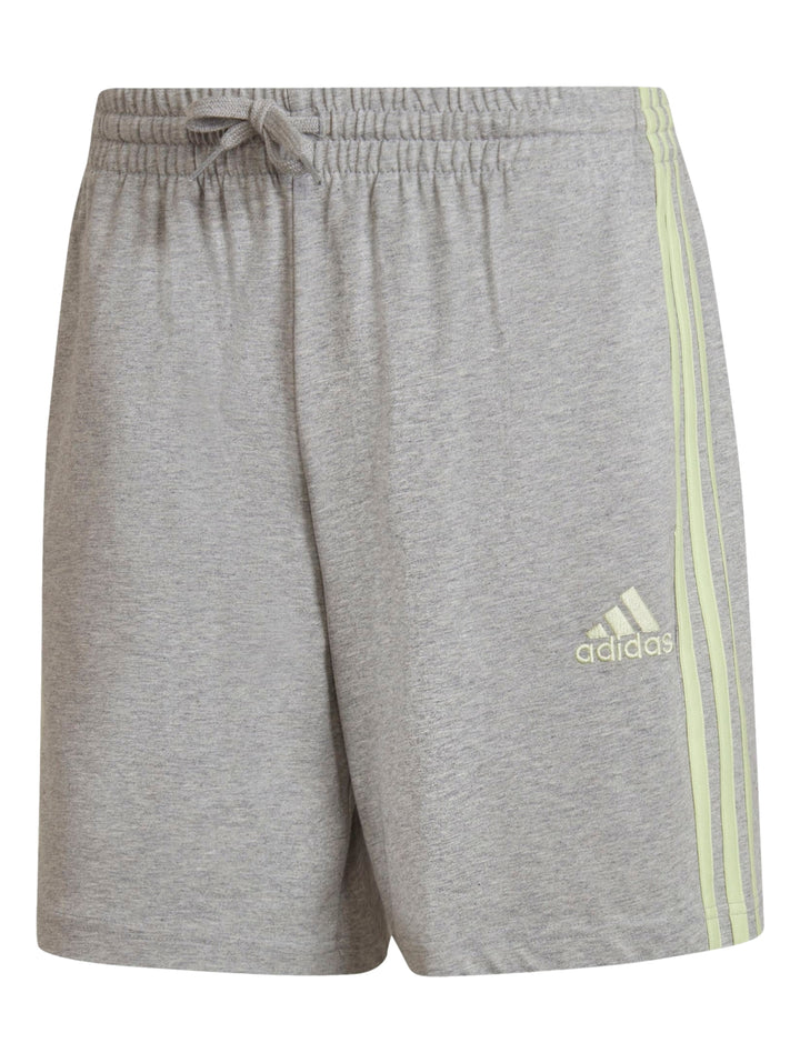 Hombre vistiendo pantalones cortos deportivos Adidas color gris con rayas laterales verde lima.