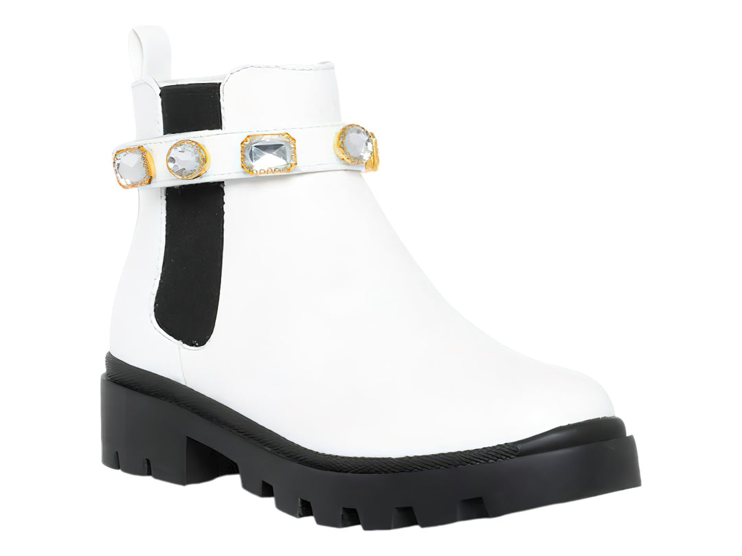 Bota blanca de tobillo con suela negra track y correa decorada con cristales.