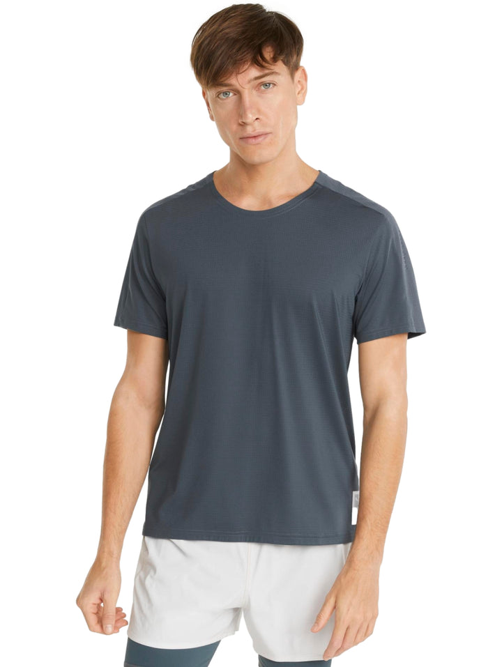 Hombre vistiendo una camiseta deportiva PUMA de color gris oscuro y shorts blancos.