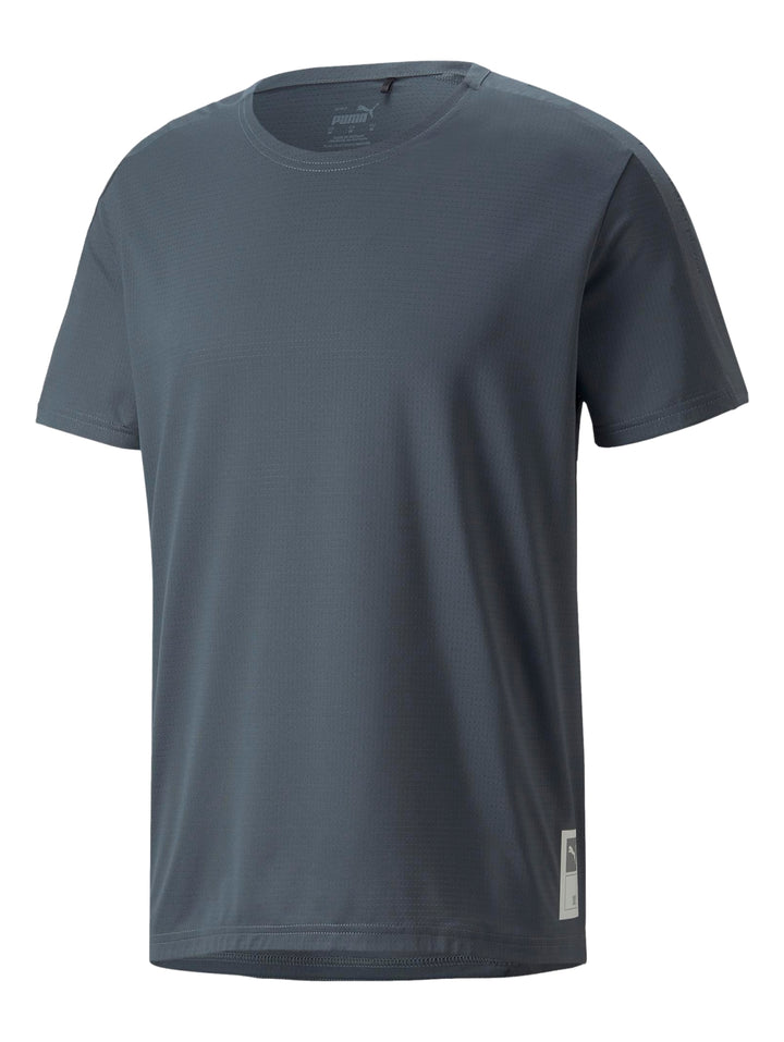 Hombre vistiendo una camiseta deportiva PUMA de color gris oscuro y shorts blancos.