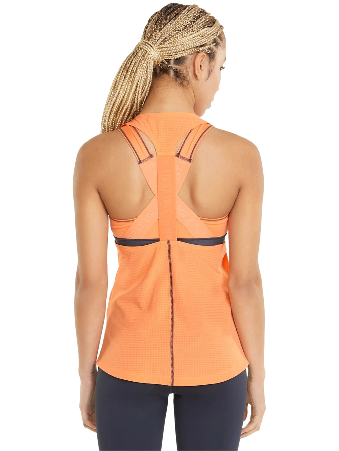 Mujer vistiendo una camiseta deportiva sin mangas color naranja Deep Apricot de PUMA.