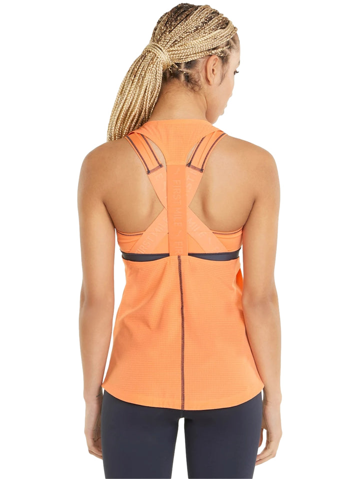 Mujer vistiendo una camiseta deportiva sin mangas color naranja Deep Apricot de PUMA.