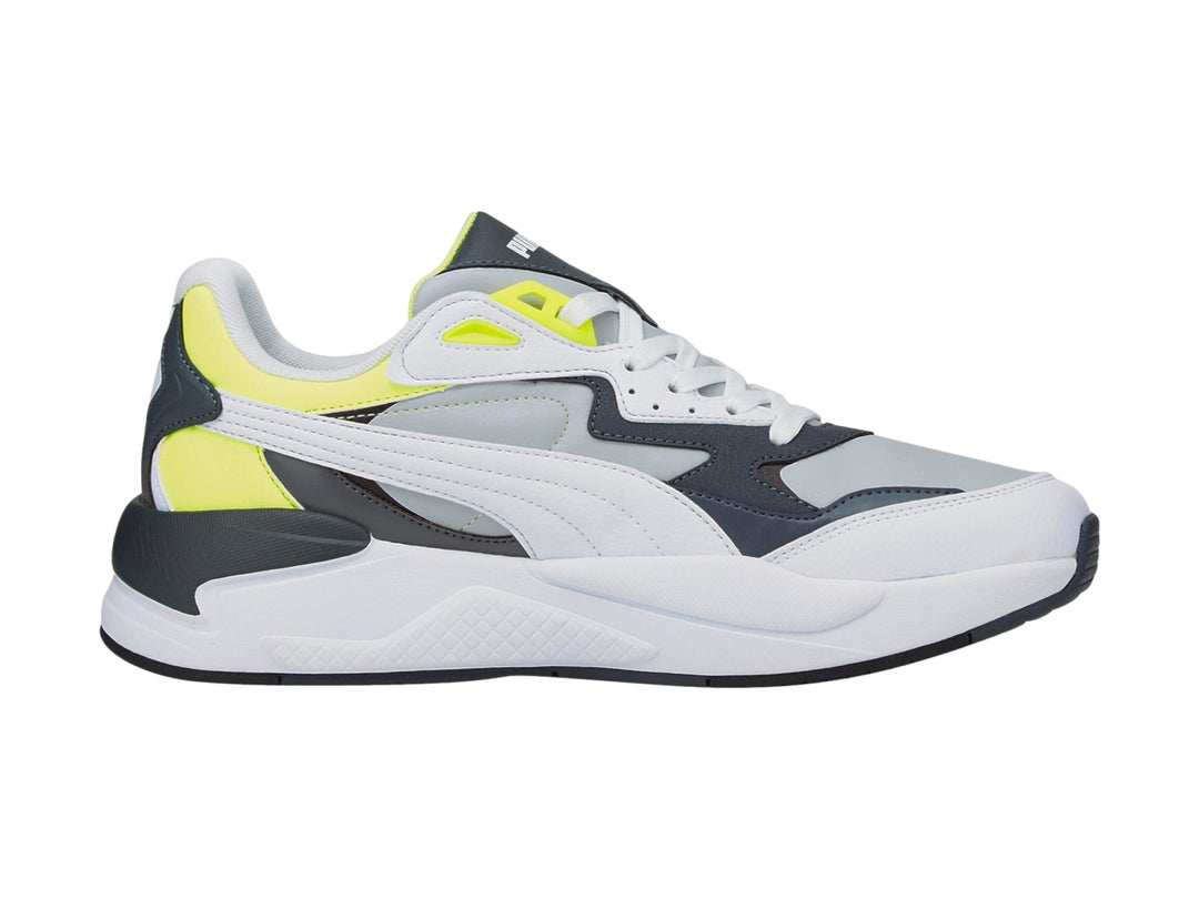 Tenis deportivos PUMA en colores blanco y gris con detalles en amarillo neón y suela blanca.