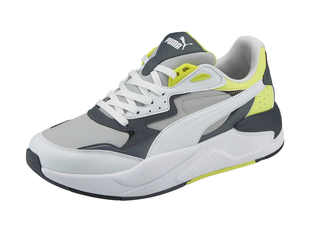 Tenis deportivos PUMA en colores blanco y gris con detalles en amarillo neón y suela blanca.