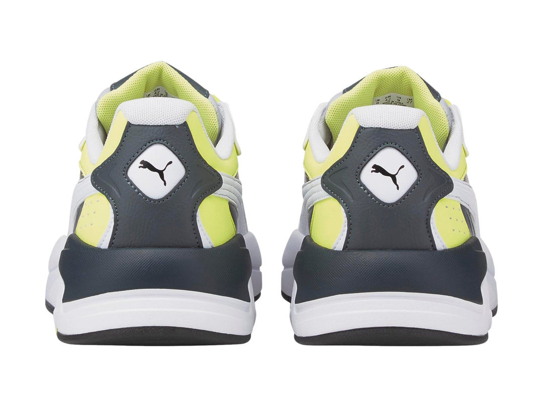 Tenis deportivos PUMA en colores blanco y gris con detalles en amarillo neón y suela blanca.
