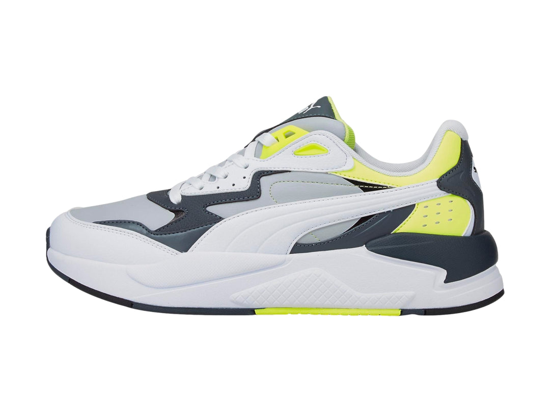 Tenis deportivos PUMA en colores blanco y gris con detalles en amarillo neón y suela blanca.