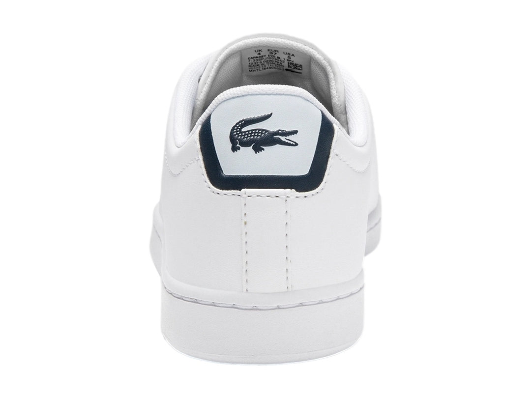 Tenis Lacoste blancos para niño con detalles en azul marino y logotipo de cocodrilo verde en el lateral.
