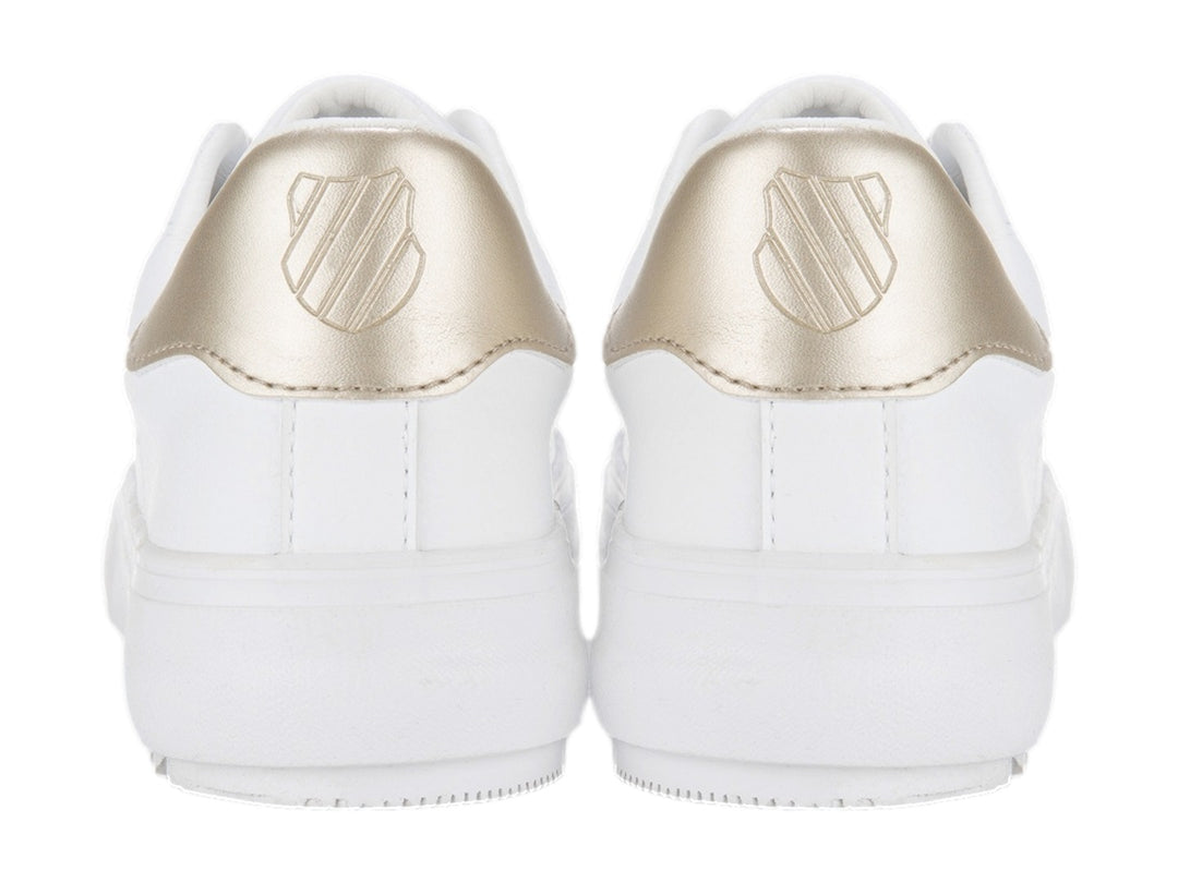 Tenis blancos K-Swiss con detalle dorado en el talón y cordones blancos.