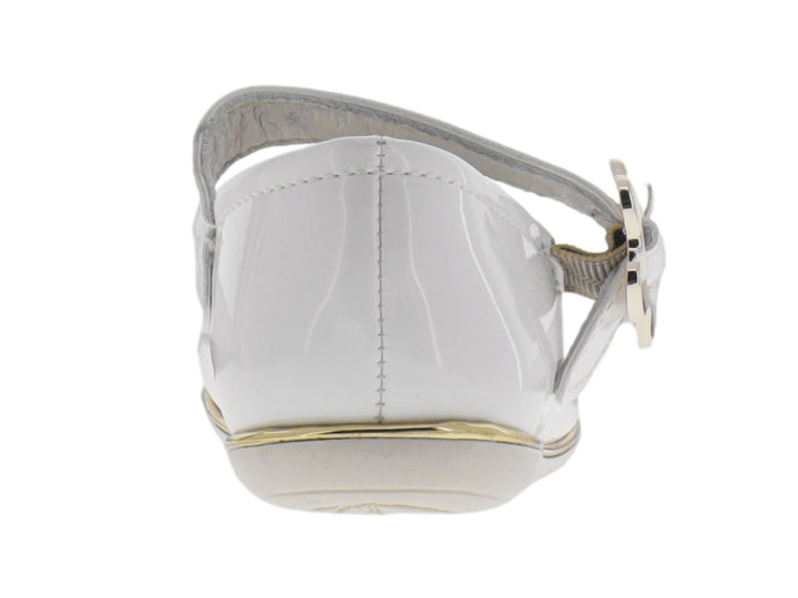 Zapatilla plana blanca brillante para niña con correa y detalle de moño dorado.