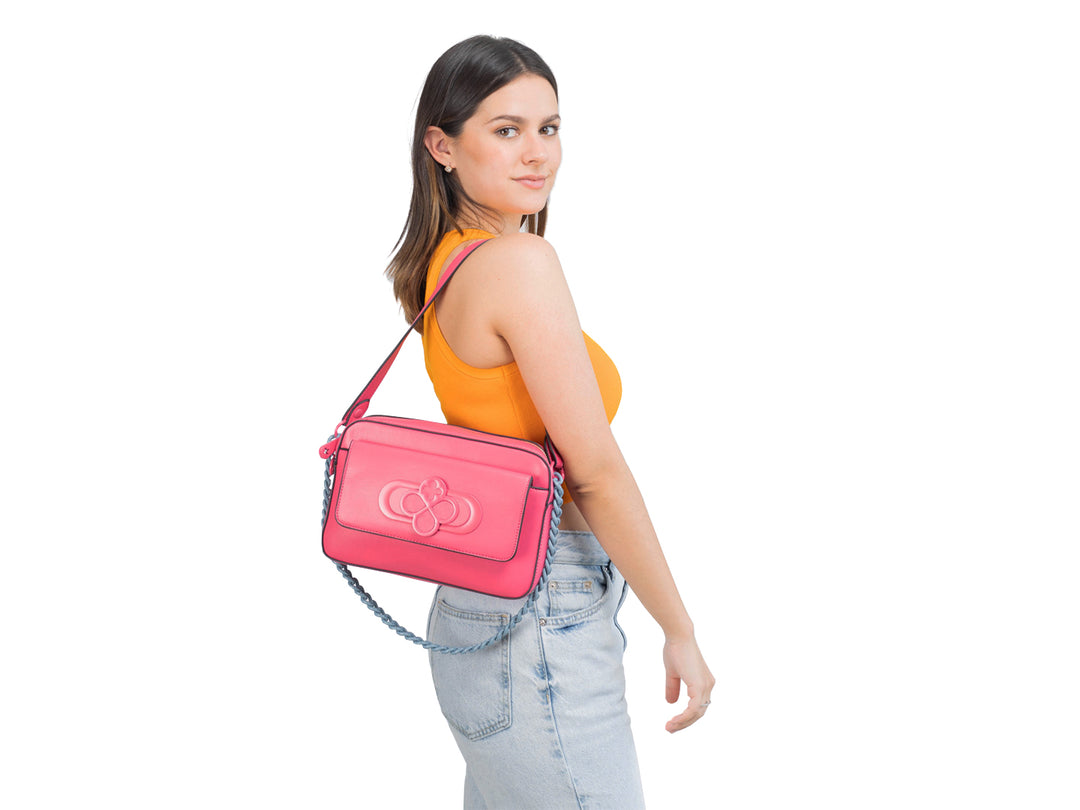 Bolso rectangular color rosa con correa de cadena azul y detalle en relieve frontal.