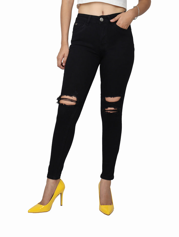 Jeans skinny color negro con detalles de destrucción en las rodillas.
