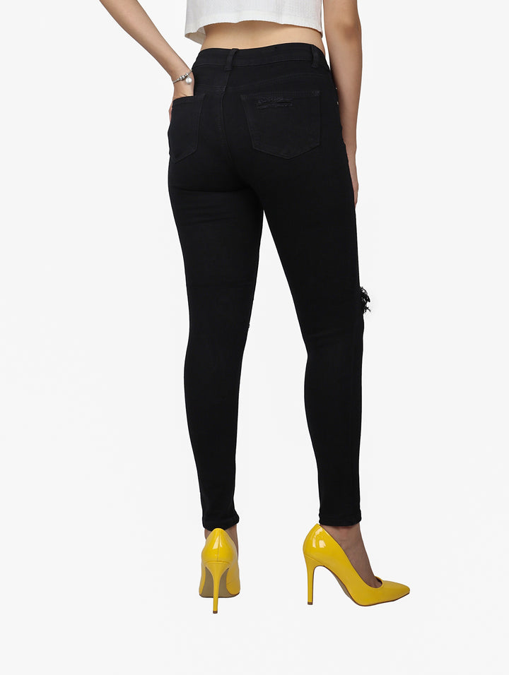 Jeans skinny color negro con detalles de destrucción en las rodillas.