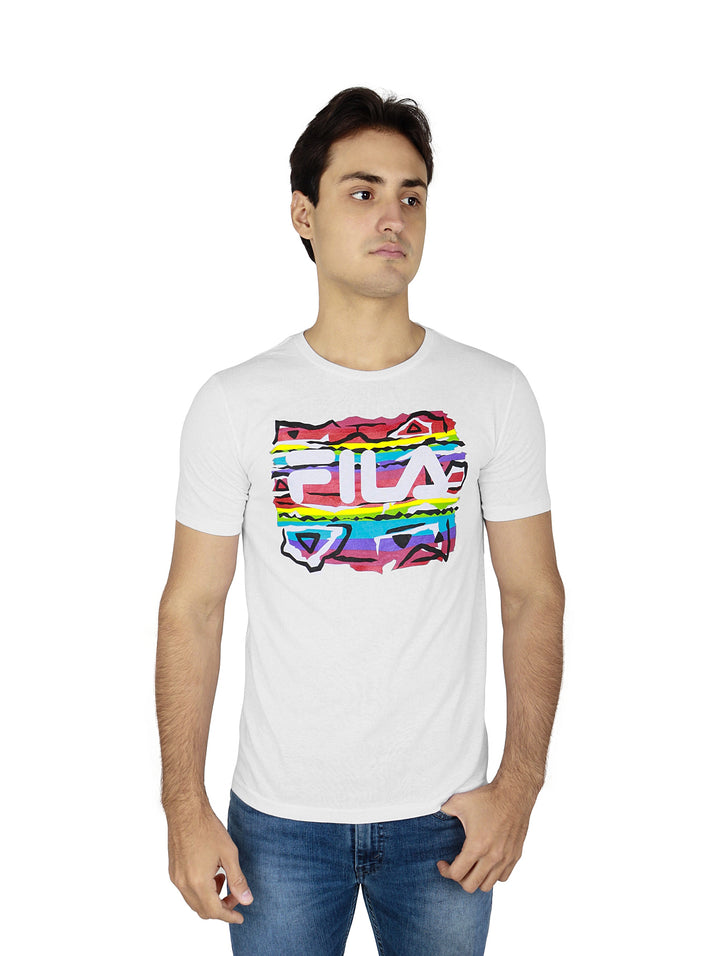 Hombre vistiendo playera blanca FILA con estampado colorido en el pecho y pantalones de mezclilla azules.