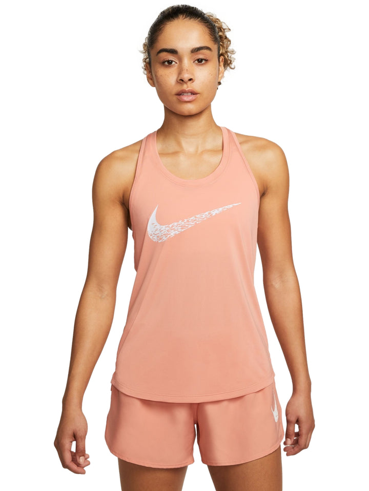 Mujer vistiendo camiseta deportiva sin mangas y shorts color coral con logo de Nike en blanco.