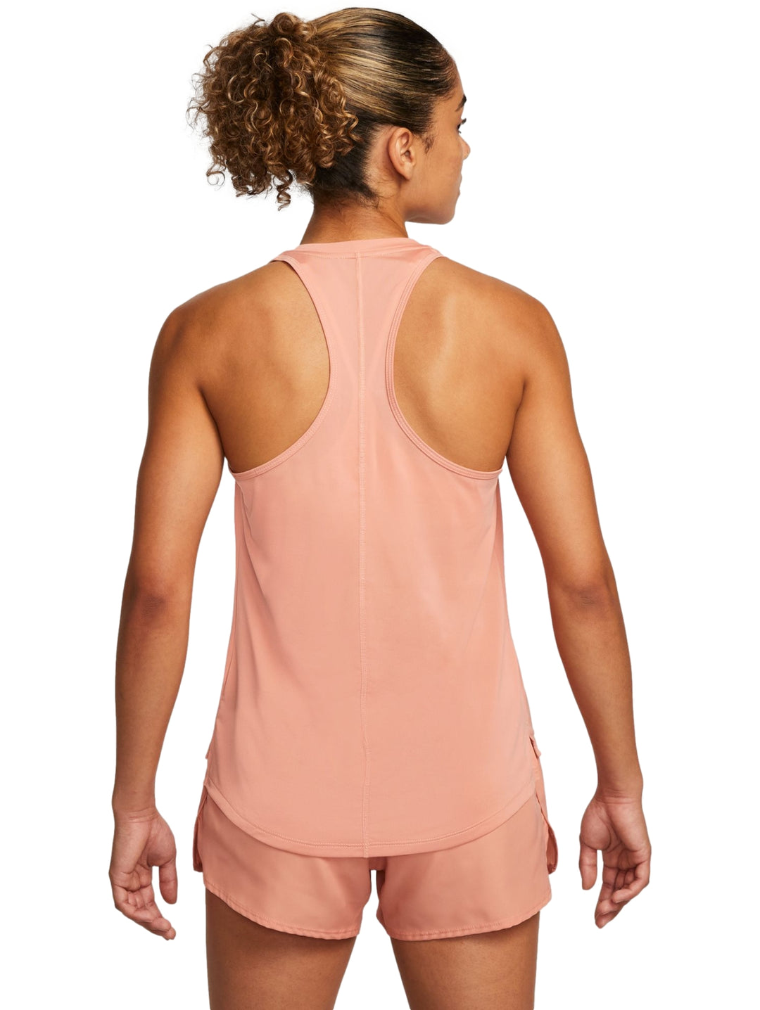 Mujer vistiendo camiseta deportiva sin mangas y shorts color coral con logo de Nike en blanco.