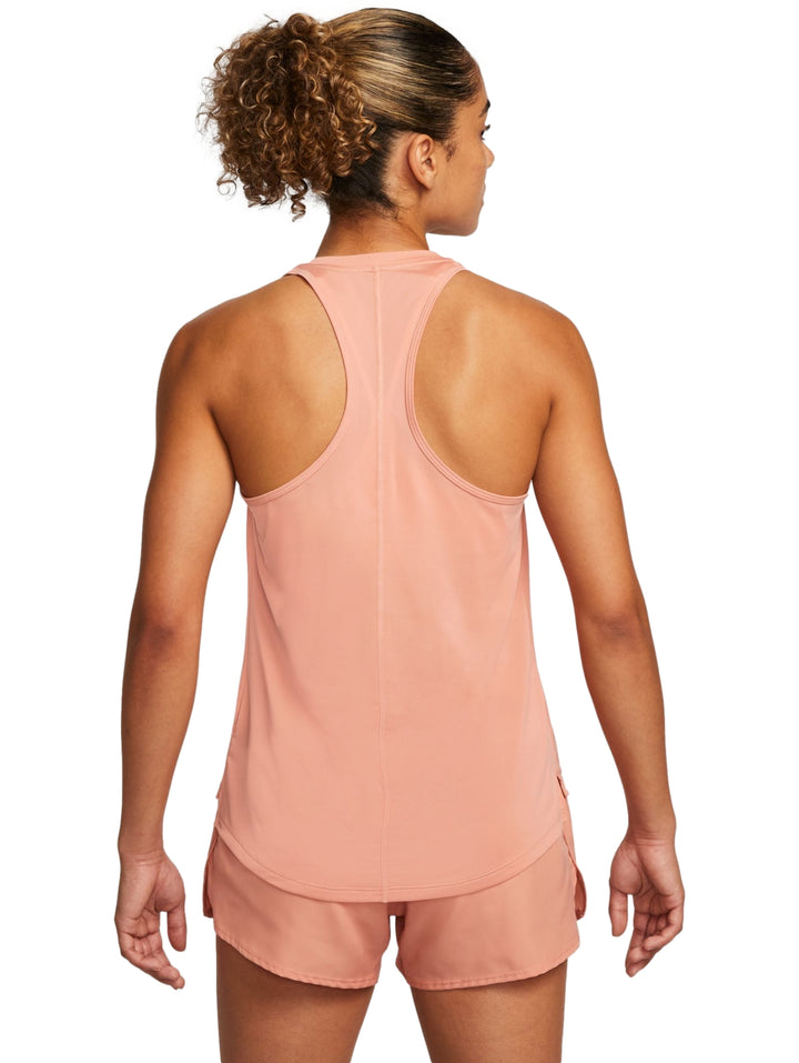 Mujer vistiendo camiseta deportiva sin mangas y shorts color coral con logo de Nike en blanco.