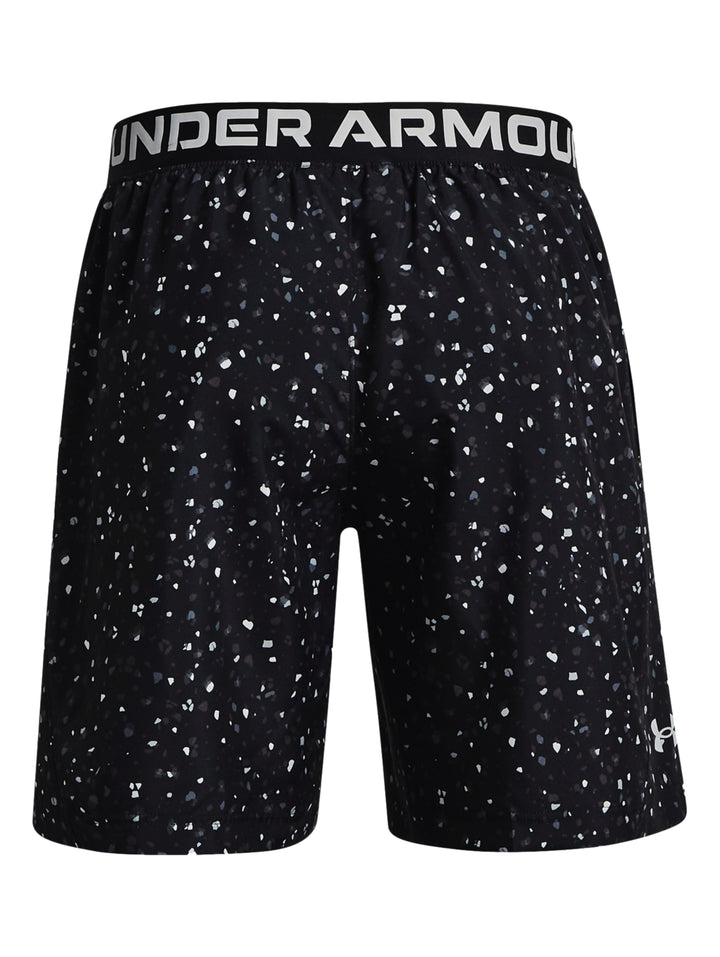 Hombre vistiendo shorts deportivos Under Armour color negro con estampado de pequeños puntos blancos.