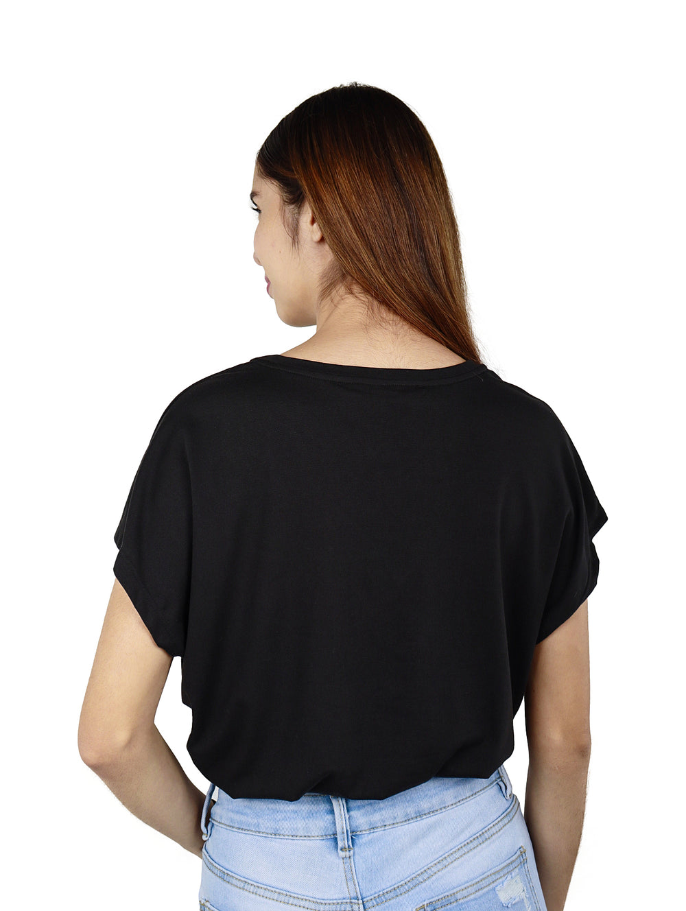Mujer joven vistiendo una blusa negra de manga corta y pantalones vaqueros azul claro.
