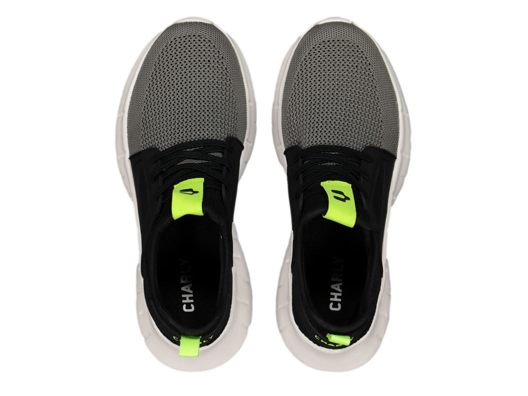 Tenis deportivos Charly color negro y gris con suela blanca y detalles en amarillo neón.