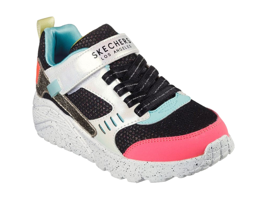 Tenis deportivos Skechers infantiles en colores negro, blanco, rosa y dorado con correa de velcro.