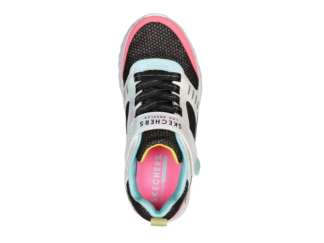 Tenis deportivos Skechers infantiles en colores negro, blanco, rosa y dorado con correa de velcro.