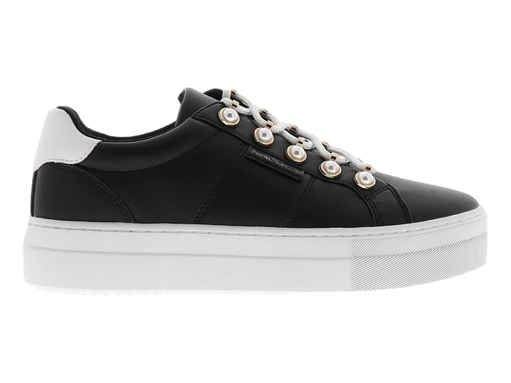 Tenis Nine West color negro con suela de plataforma blanca y ojillos dorados.