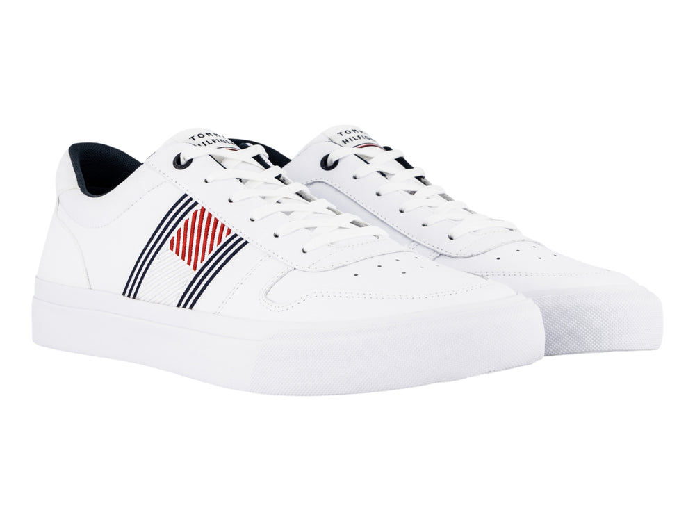 Tenis blancos de cuero Tommy Hilfiger con detalles laterales en azul y rojo y suela blanca.