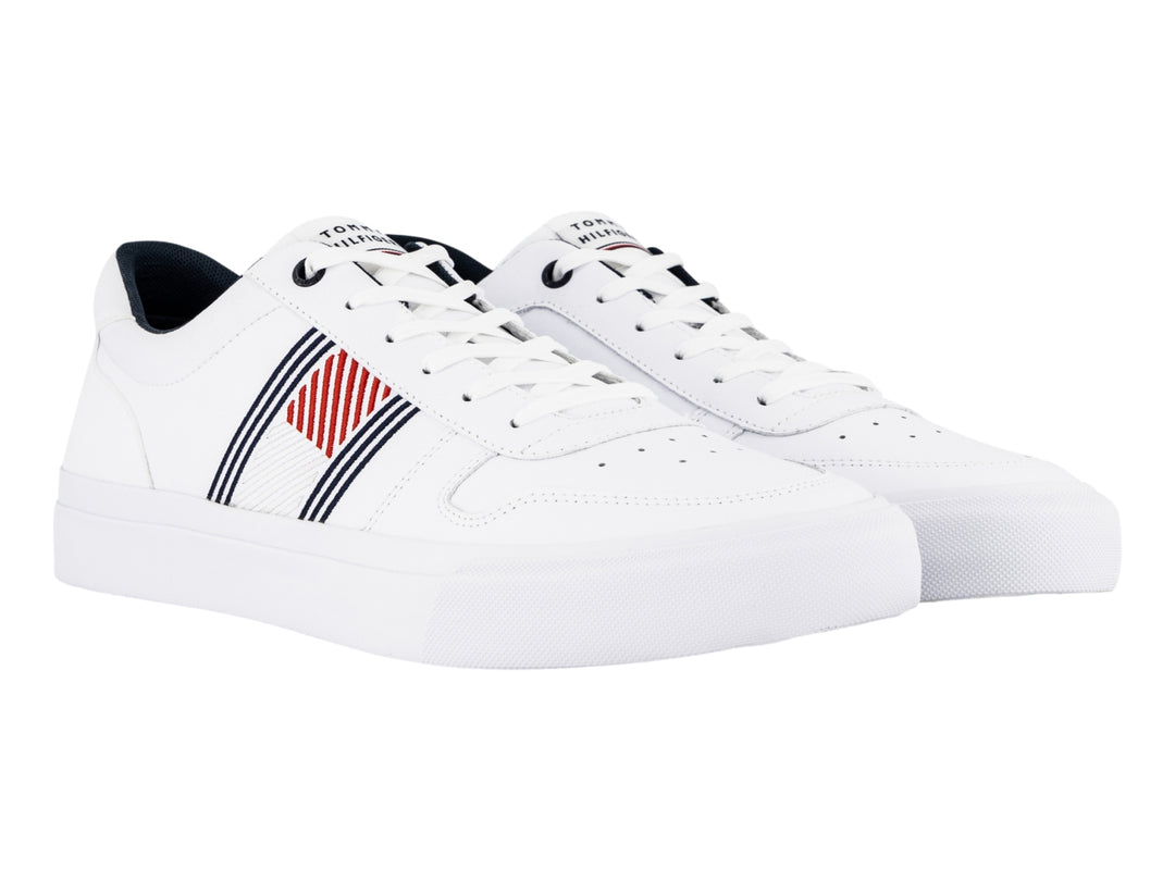 Tenis blancos de cuero Tommy Hilfiger con detalles laterales en azul y rojo y suela blanca.