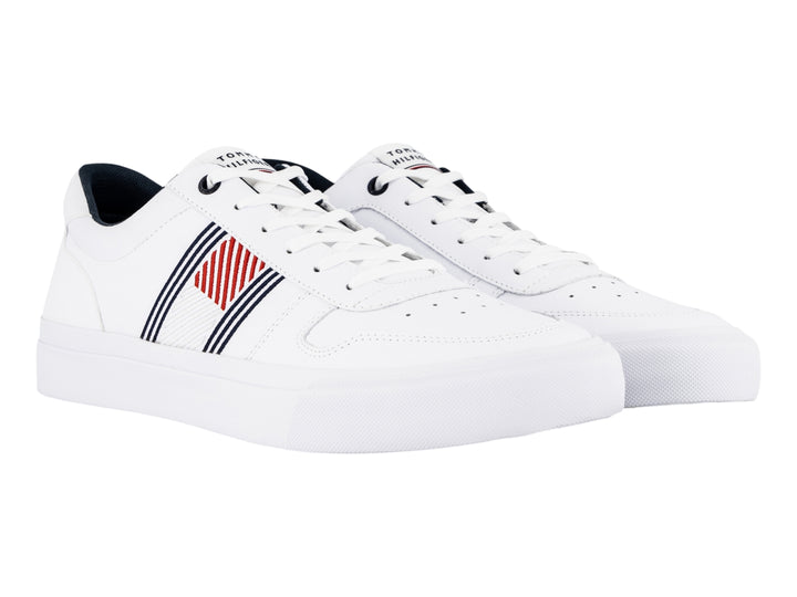 Tenis blancos de cuero Tommy Hilfiger con detalles laterales en azul y rojo y suela blanca.
