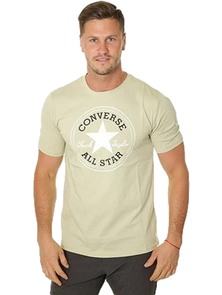 Hombre vistiendo playera Converse color verde oliva con logotipo blanco en el pecho.