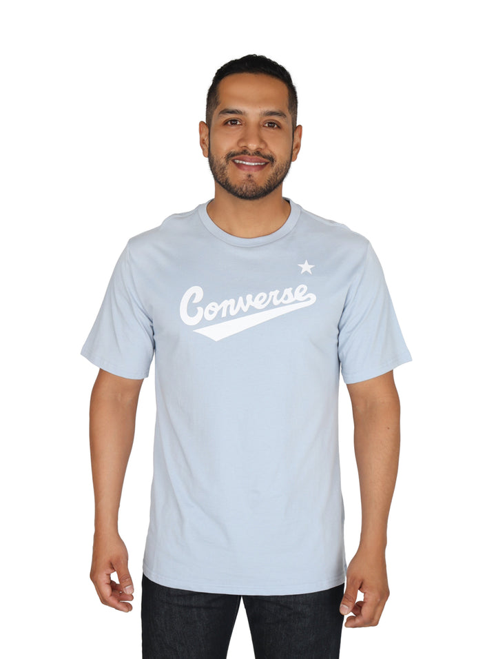 Hombre usando una playera Converse de color azul claro con logotipo blanco en el pecho.