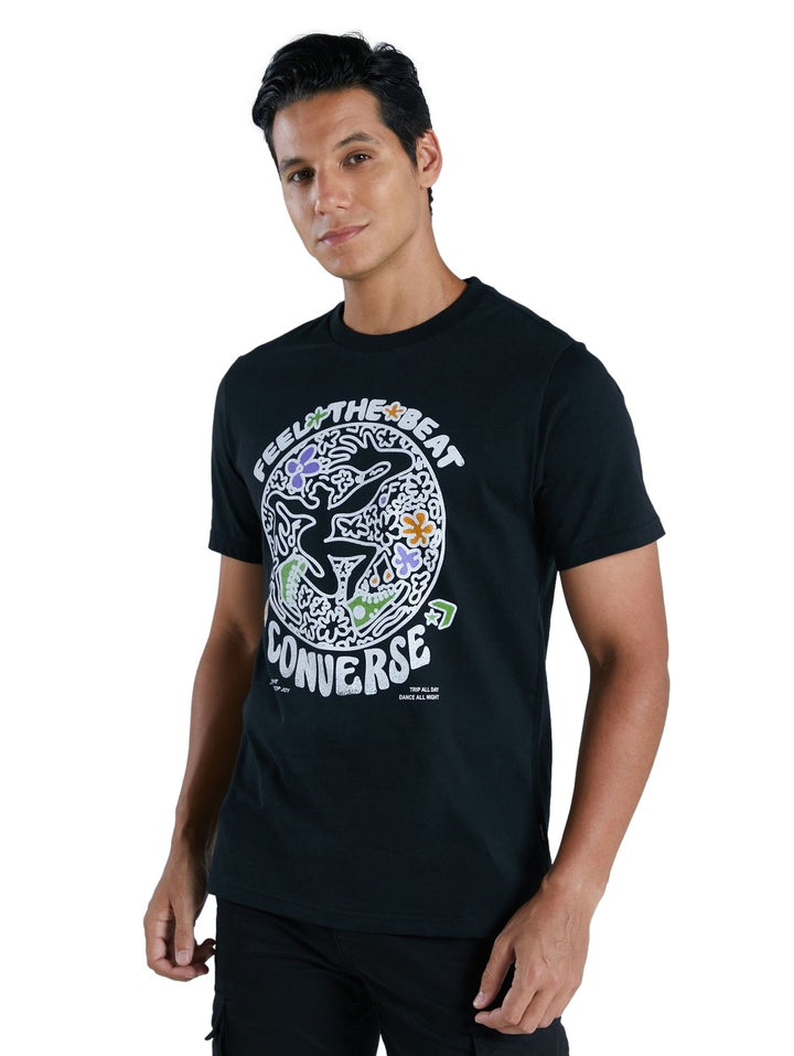 Hombre vistiendo playera negra de manga corta con estampado gráfico colorido de Converse en el pecho.