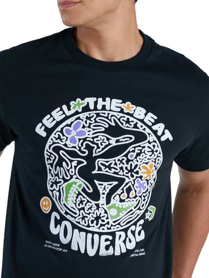 Hombre vistiendo playera negra de manga corta con estampado gráfico colorido de Converse en el pecho.