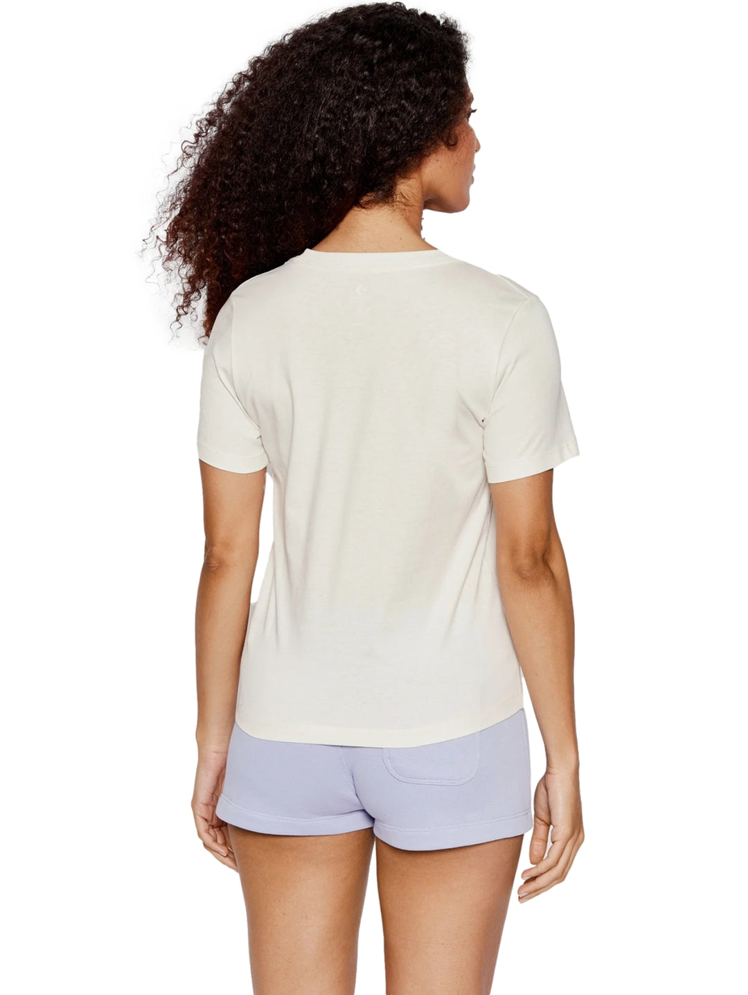 Mujer vistiendo playera Converse color blanco vintage con logotipo morado y shorts morados.